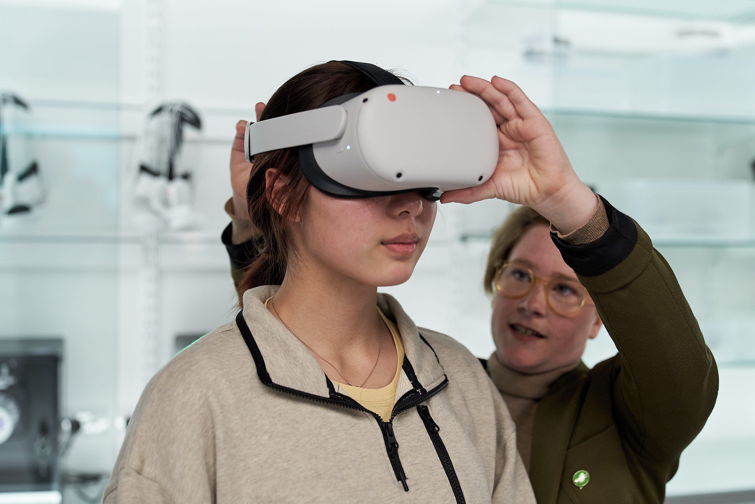 A woman putting a VR headset on a young person
