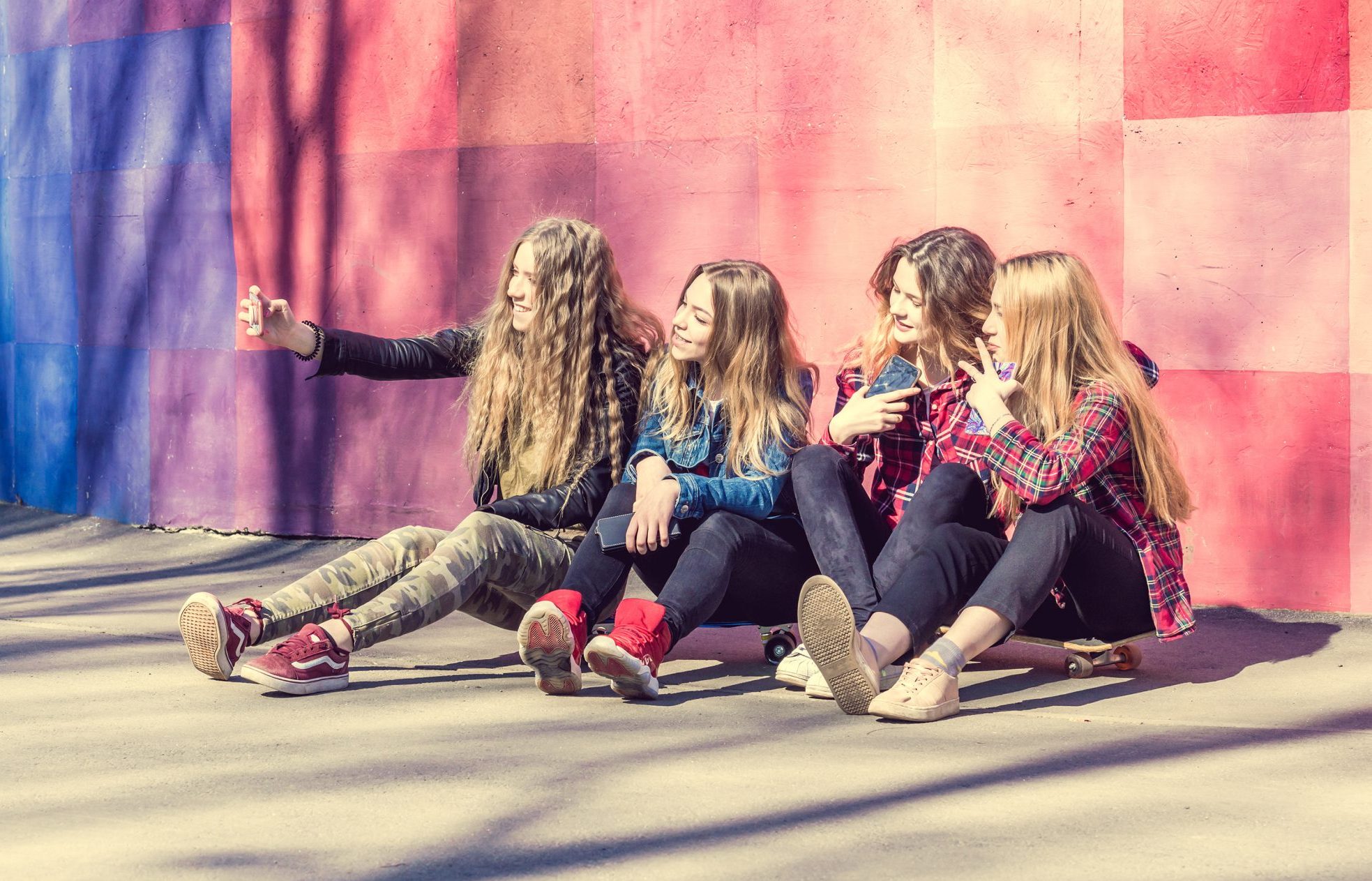Group of young people sitting on the ground looking at a phone