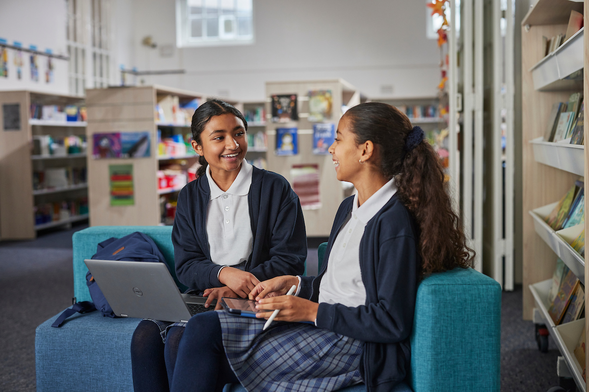 Two students with a laptop in a library